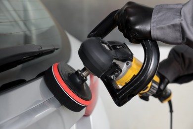 Photo of Man polishing car with orbital polisher indoors, closeup