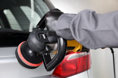 Photo of Man polishing car with orbital polisher indoors, closeup