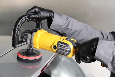 Photo of Man polishing car with orbital polisher indoors, closeup