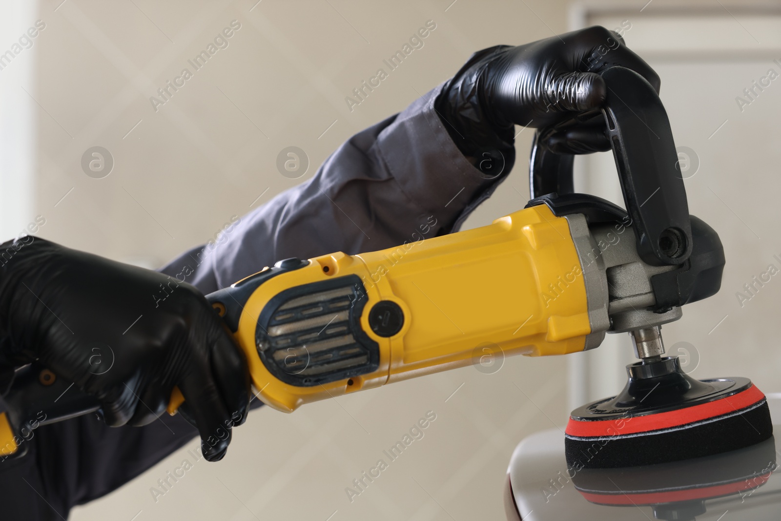 Photo of Man polishing car with orbital polisher indoors, closeup