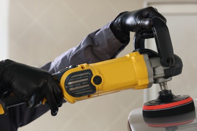 Photo of Man polishing car with orbital polisher indoors, closeup