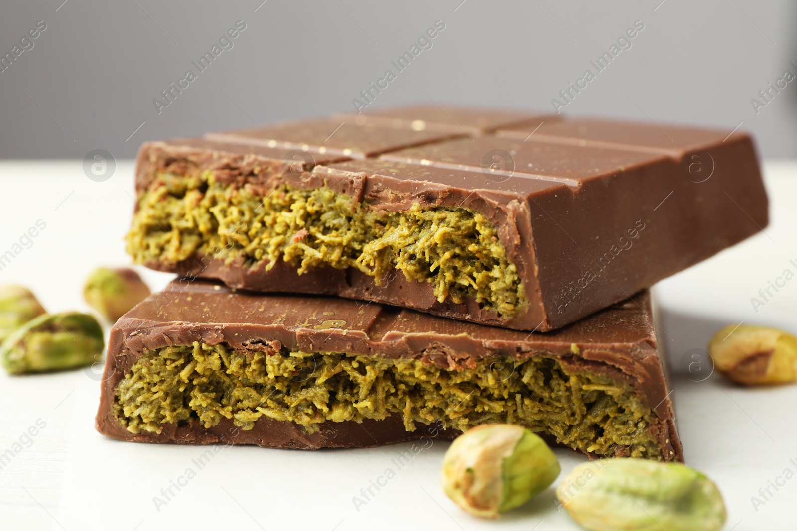 Photo of Pieces of tasty Dubai chocolate with pistachios and knafeh on white wooden table, closeup