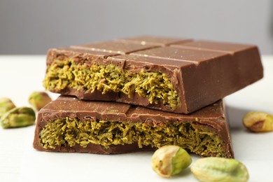 Photo of Pieces of tasty Dubai chocolate with pistachios and knafeh on white wooden table, closeup