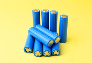 Photo of Many AA cell batteries on yellow background, closeup