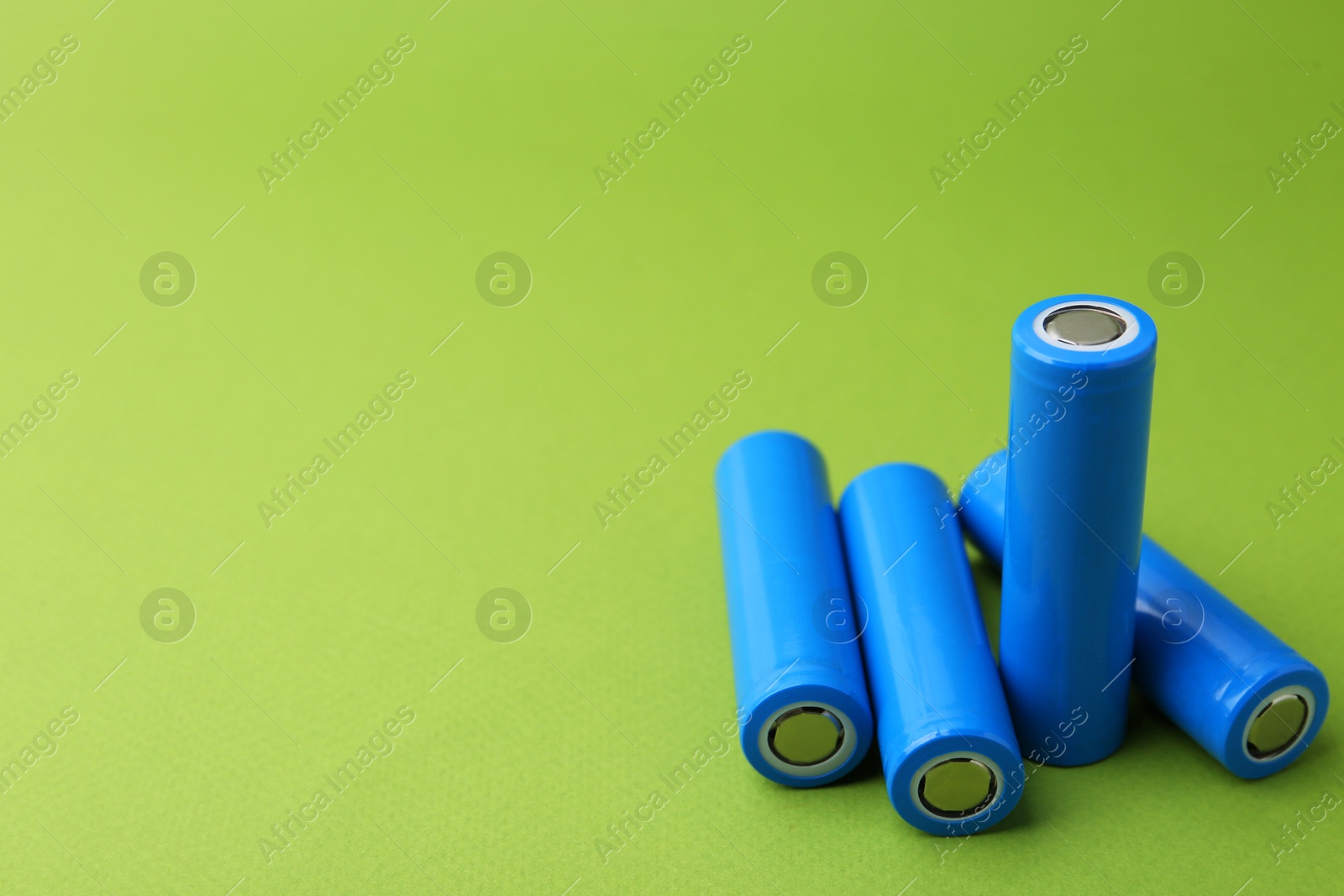 Photo of Many AA cell batteries on green background, closeup. Space for text