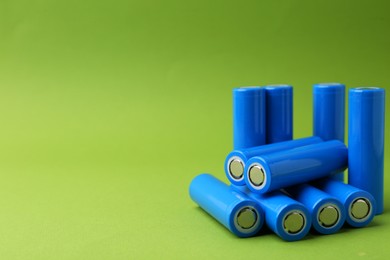 Photo of Many AA cell batteries on green background, closeup. Space for text