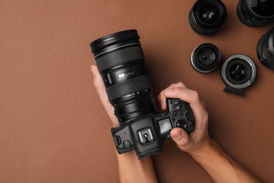 Photo of Photographer with professional camera on brown background, top view