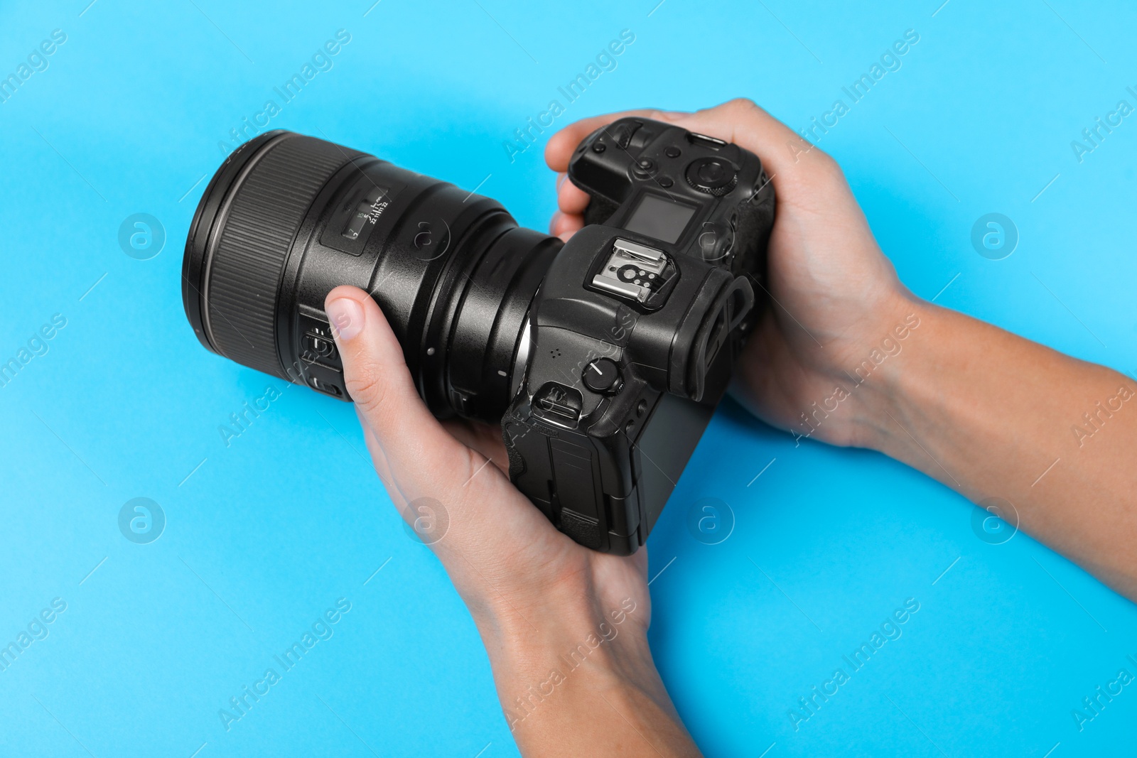 Photo of Photographer with professional camera on light blue background, above view