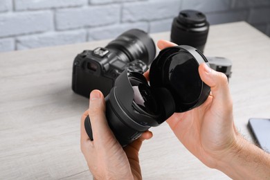 Photo of Photographer with camera lens at wooden table, closeup