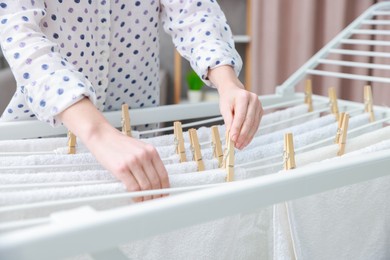 Woman hanging fresh clean laundry on drying rack at home, closeup