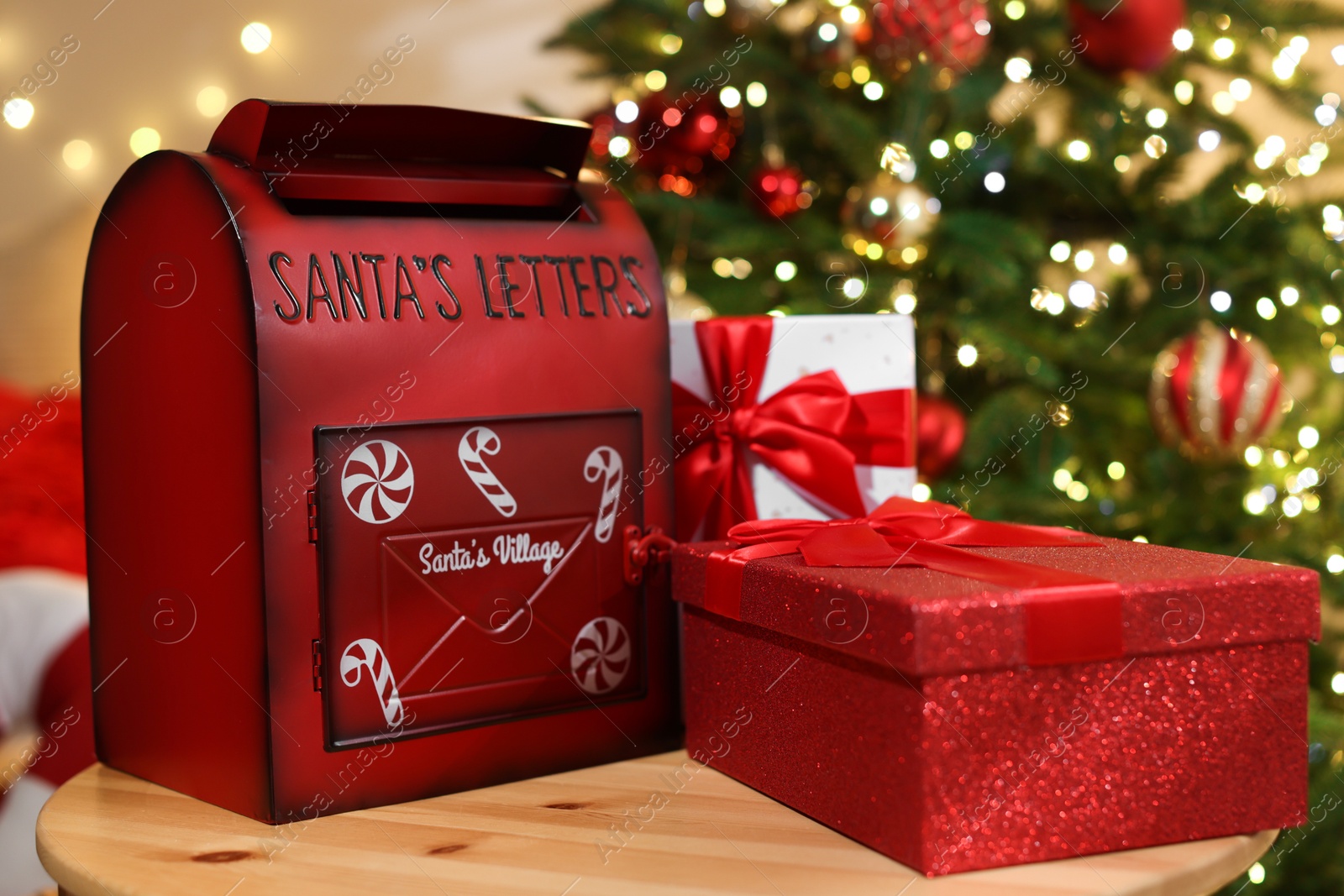 Photo of Santa Claus mailbox and gift boxes on wooden table indoors. Christmas tradition