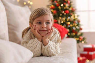 Photo of Little girl lying on sofa at home. Christmas celebration