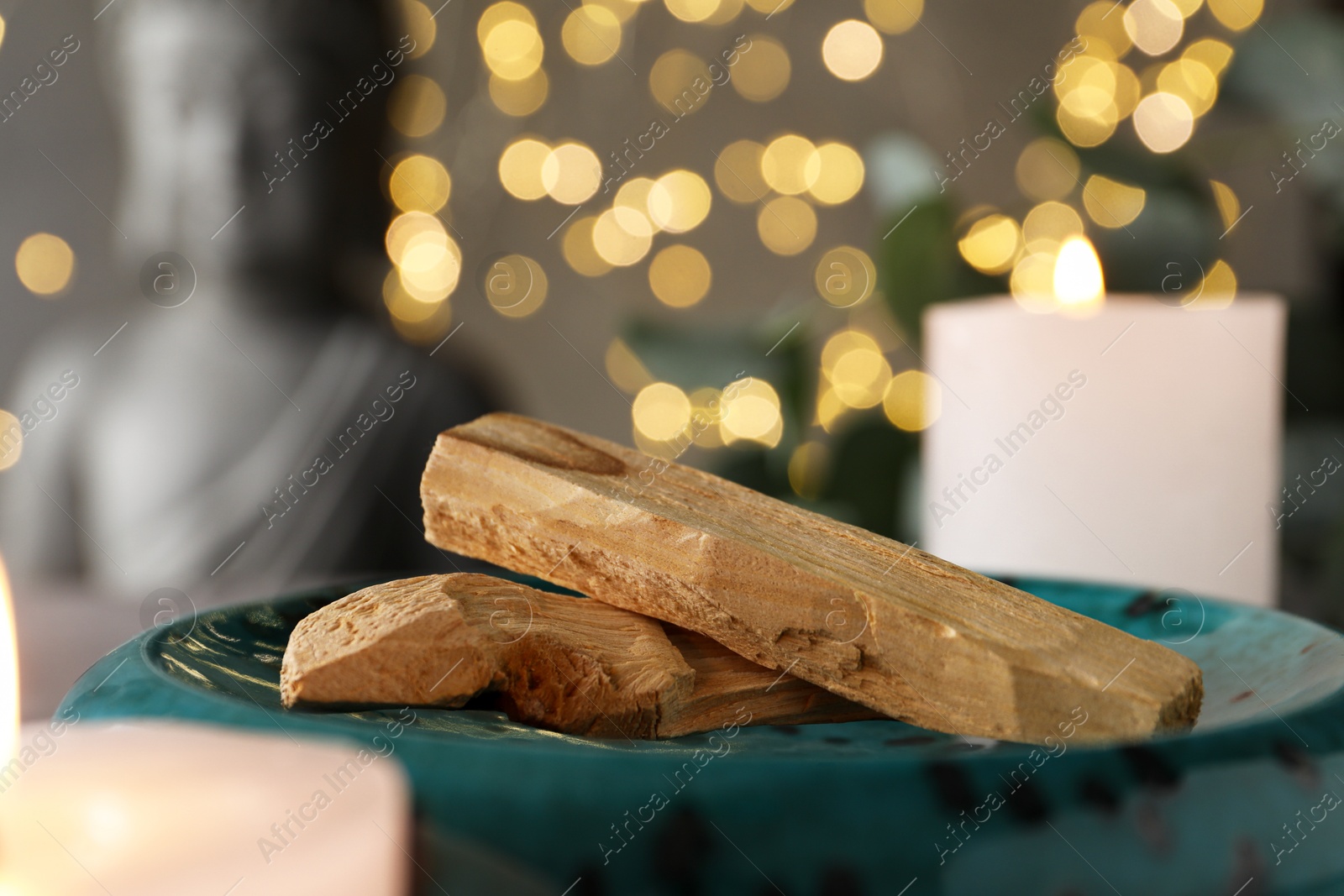 Photo of Palo santo sticks and burning candles on table, closeup