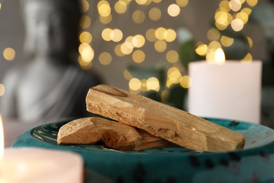 Photo of Palo santo sticks and burning candles on table, closeup