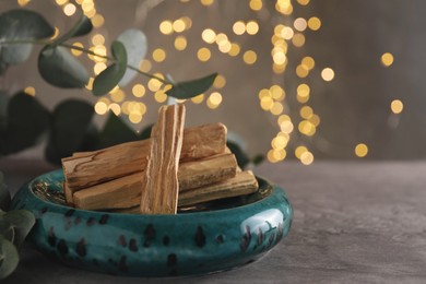 Photo of Palo santo sticks and eucalyptus leaves on table, closeup. Space for text