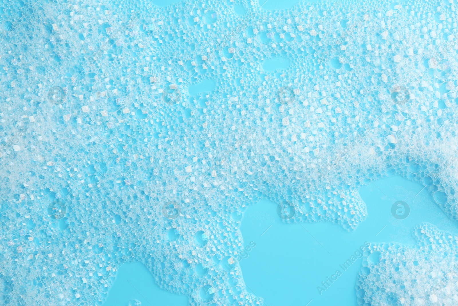 Photo of Detergent foam with bubbles on light blue background, top view