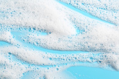 Photo of Detergent foam with bubbles on light blue background, top view