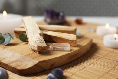 Photo of Palo santo sticks and gemstones on wicker table, closeup