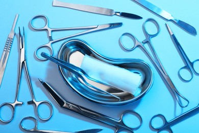 Photo of Different surgical instruments on light blue background, flat lay