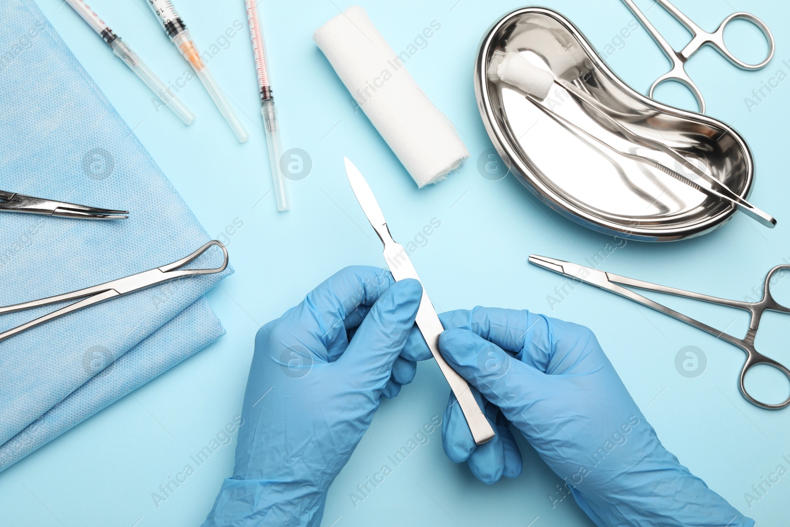 Photo of Doctor with different surgical tools on light blue background, top view