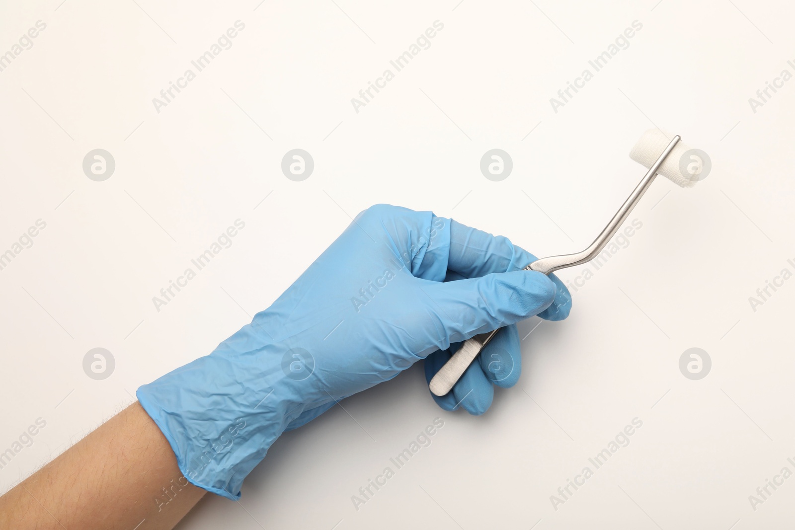 Photo of Doctor holding surgical tweezers with gauze on light background, top view