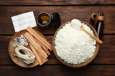 Photo of Soy wax and other supplies for making candles on wooden table, flat lay