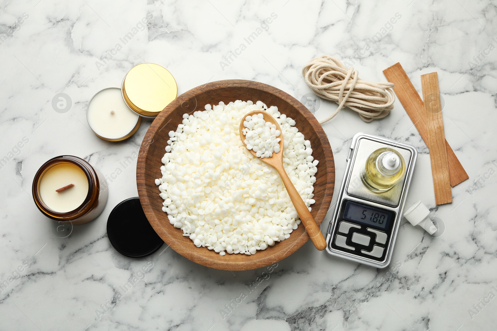 Photo of Soy wax and other supplies for making candles on white marble table, flat lay