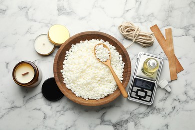 Photo of Soy wax and other supplies for making candles on white marble table, flat lay