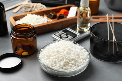 Photo of Soy wax, essential oil and different tools for making candles on gray textured table, closeup