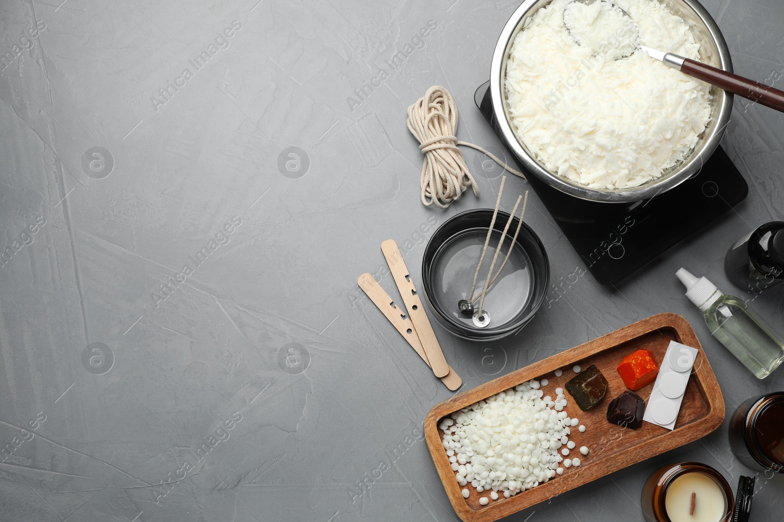 Photo of Soy wax, essential oils and different tools for making candles on gray textured table, flat lay. Space for text