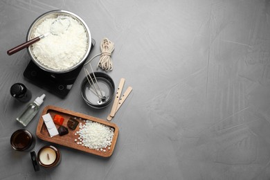 Photo of Soy wax, essential oils and different tools for making candles on gray textured table, flat lay. Space for text