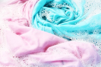 Photo of Colorful clothes soaked in water before washing, closeup