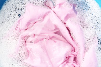 Photo of Pink clothes soaked in water before washing, top view