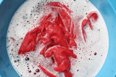 Photo of Red clothes soaked in water before washing, top view