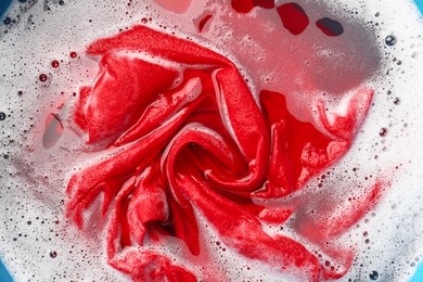 Photo of Red clothes soaked in water before washing, top view