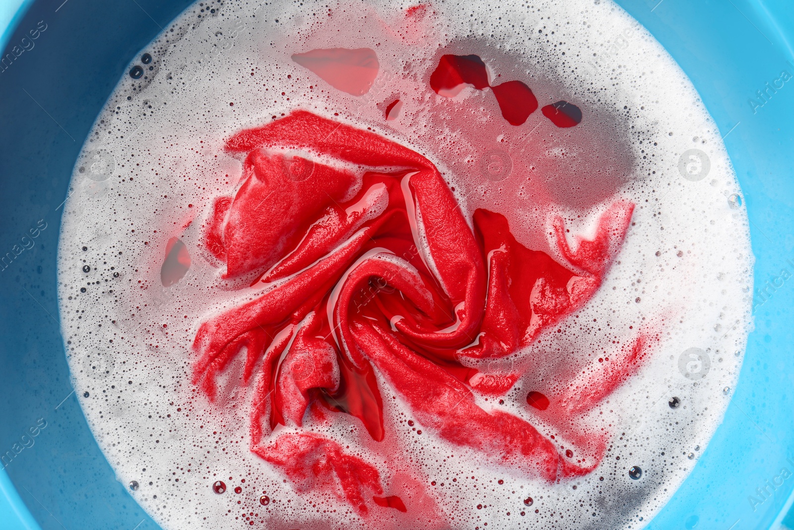 Photo of Red clothes soaked in water before washing, top view