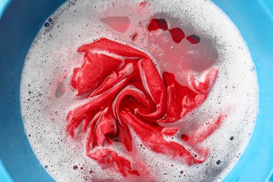 Photo of Red clothes soaked in water before washing, top view