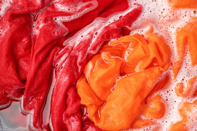 Photo of Colorful clothes soaked in water before washing, top view