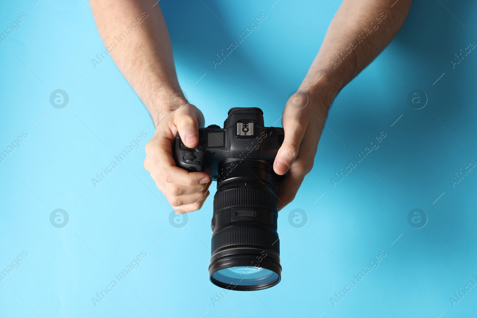 Photo of Photographer with professional camera on light blue background, above view