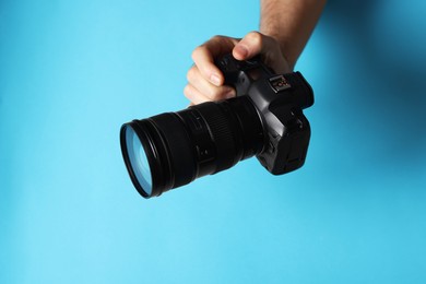 Photo of Photographer with professional camera on light blue background, closeup