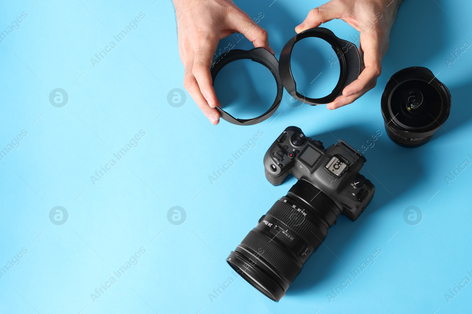 Photo of Photographer with professional camera and equipment on light blue background, top view. Space for text