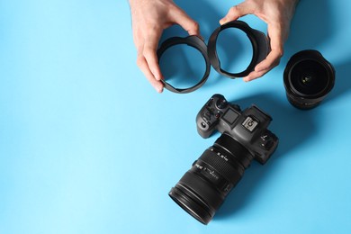 Photo of Photographer with professional camera and equipment on light blue background, top view. Space for text