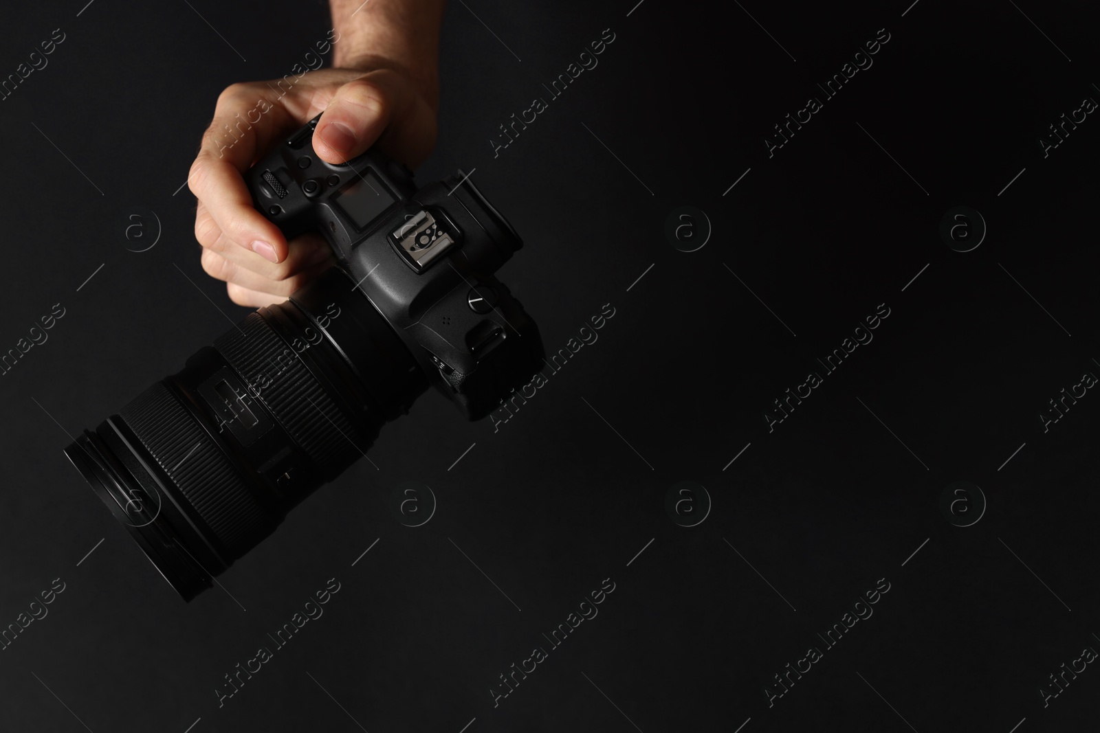 Photo of Photographer with professional camera on black background, top view. Space for text