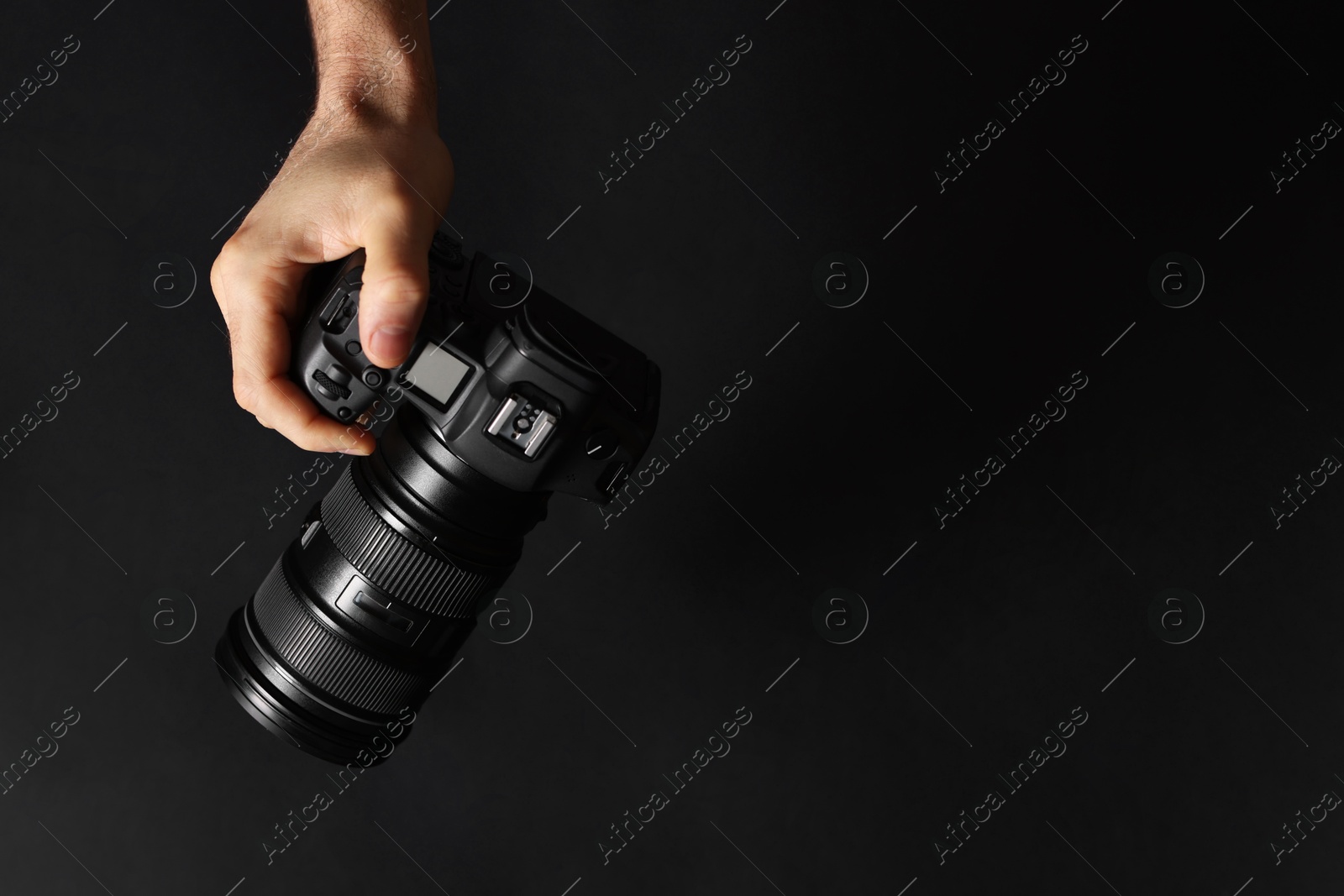 Photo of Photographer with professional camera on black background, top view. Space for text