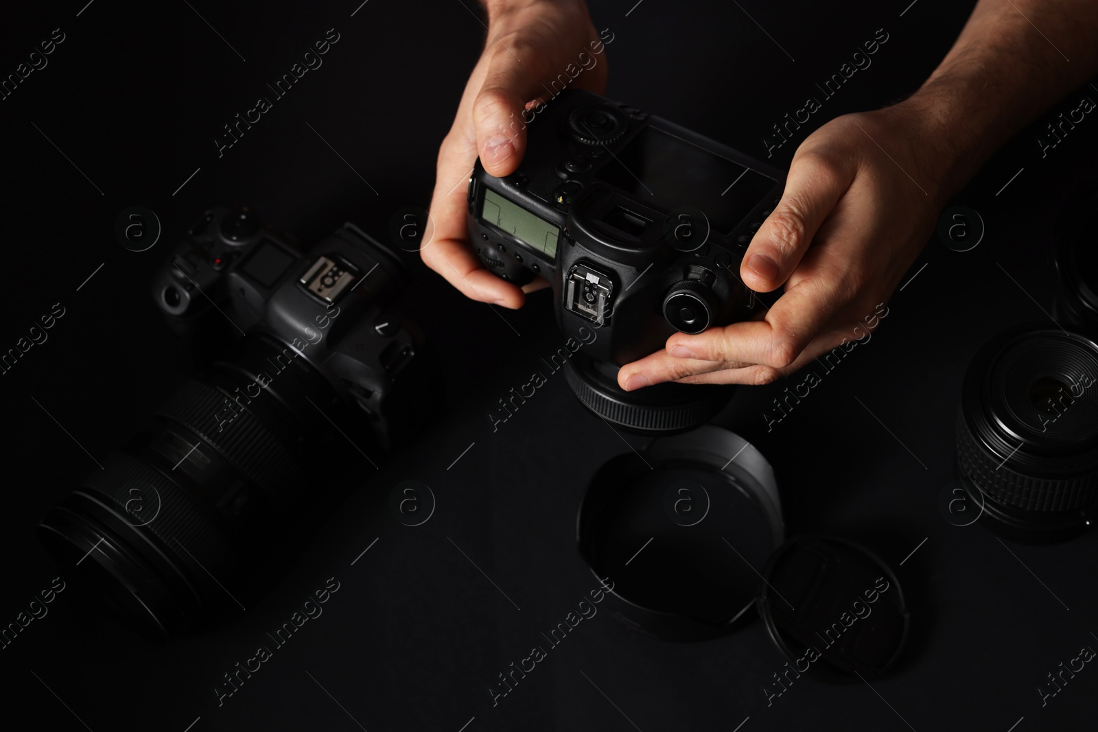 Photo of Photographer with professional camera and equipment on black background, closeup