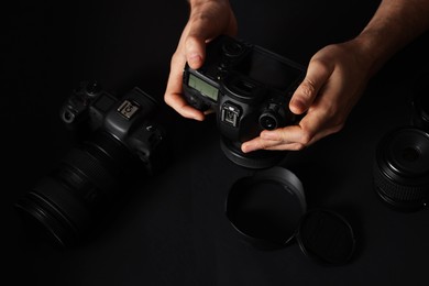 Photo of Photographer with professional camera and equipment on black background, closeup