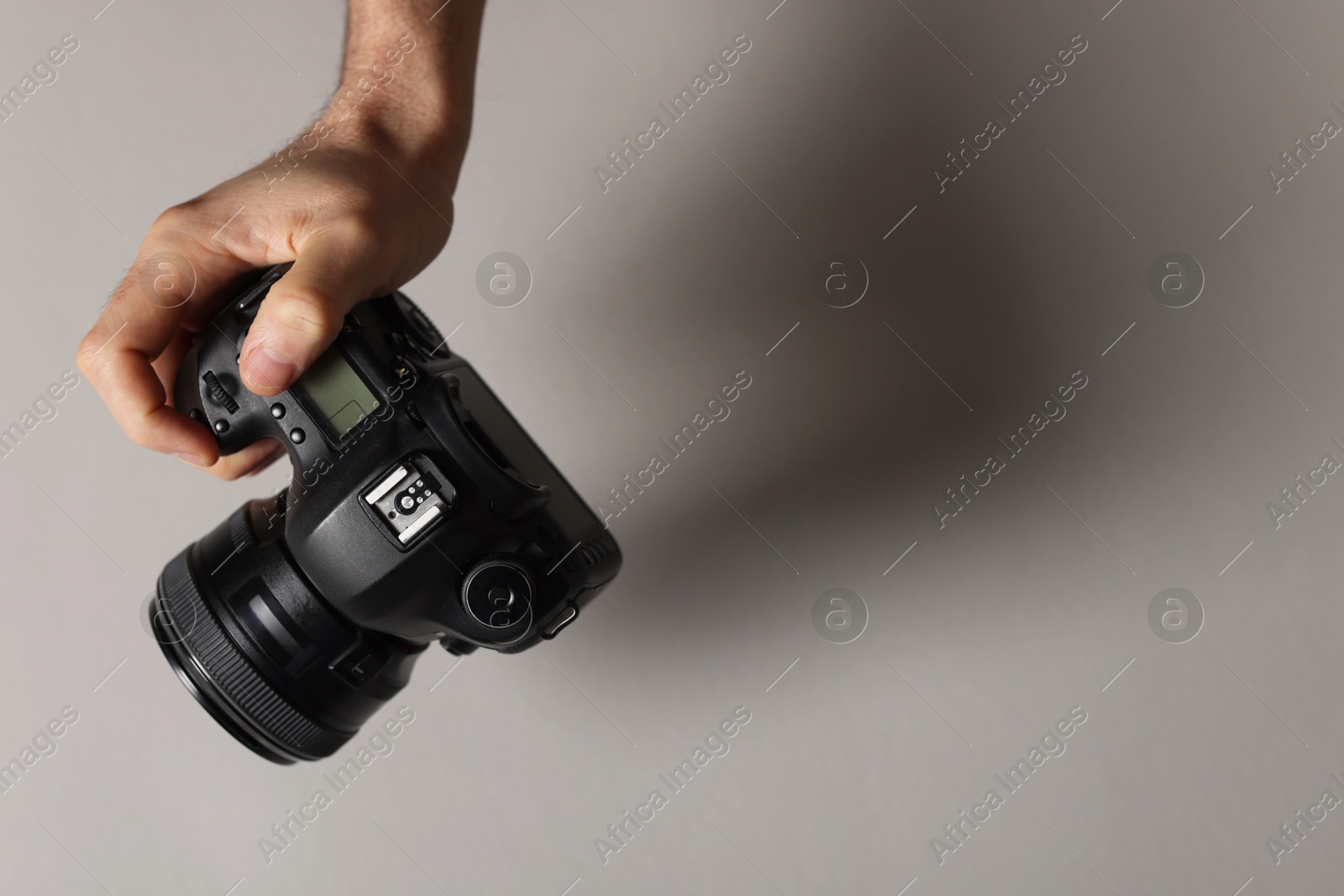 Photo of Photographer with professional camera on grey background, closeup. Space for text