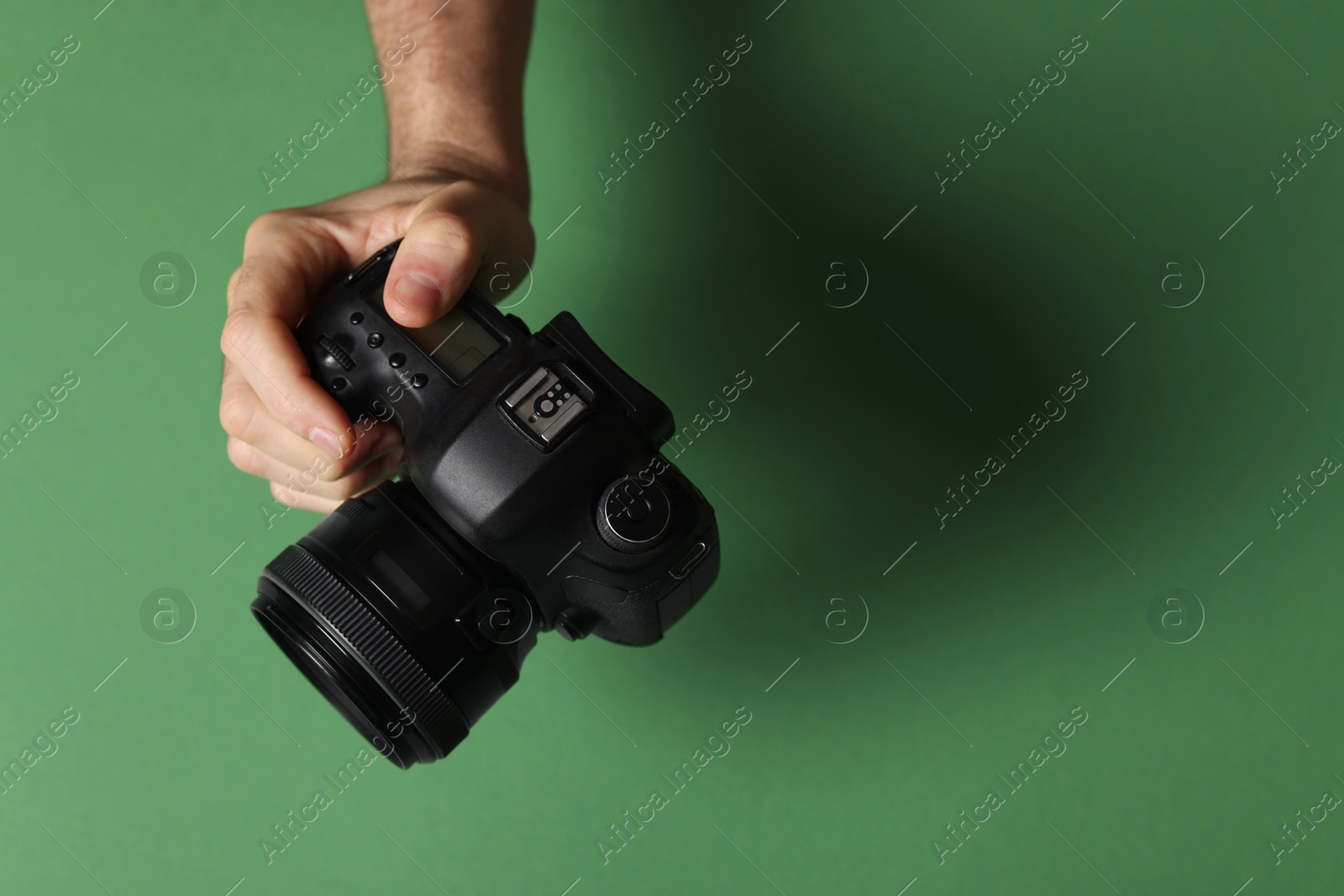 Photo of Photographer with professional camera on green background, closeup. Space for text