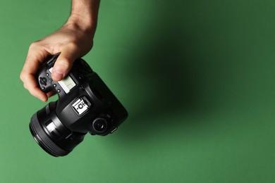 Photo of Photographer with professional camera on green background, closeup. Space for text