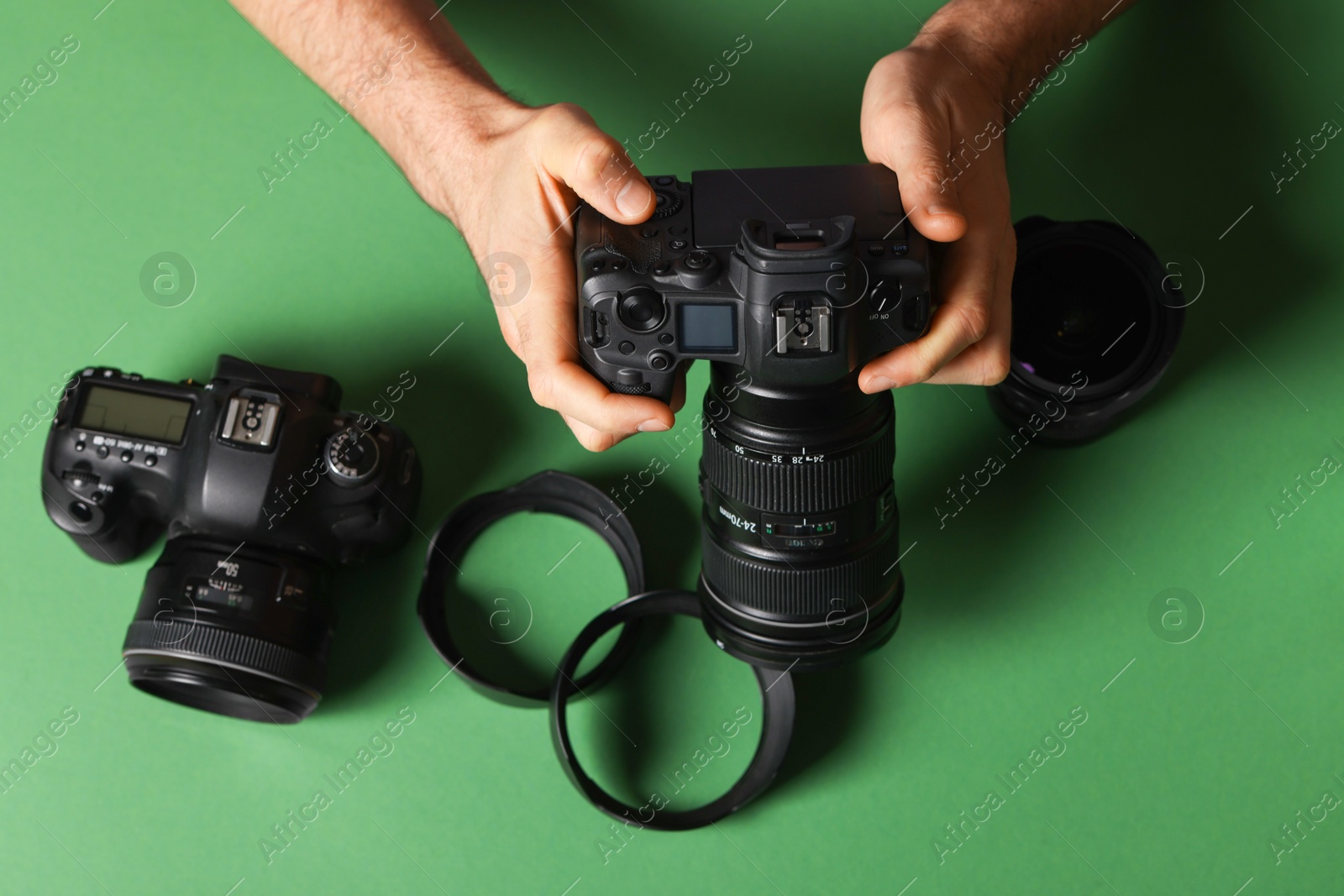 Photo of Photographer with professional camera and equipment on green background, top view